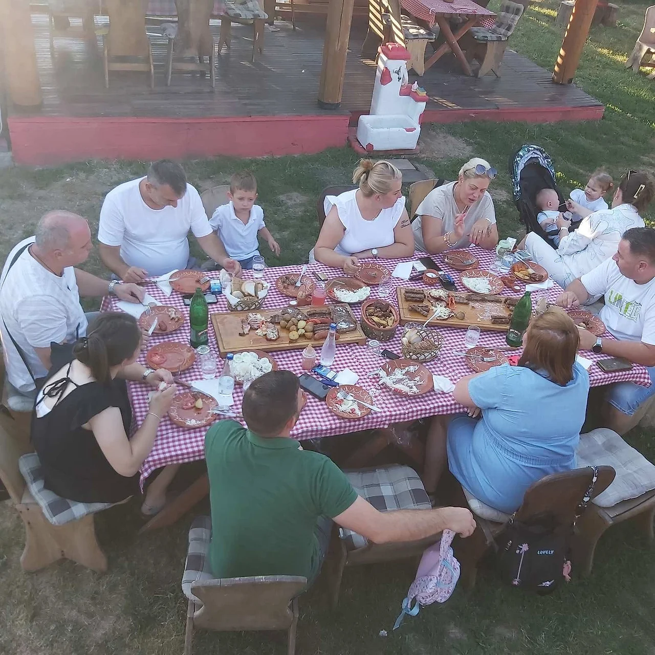 Druženje gostiju za trpezom u bašti