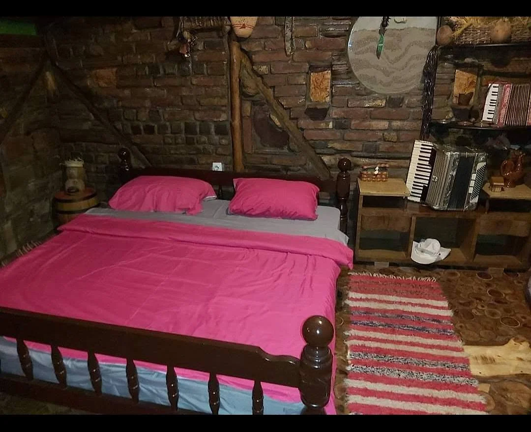 Potkrovna soba sa drvenim krevetom i roze posteljinom